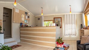 A reception area with a wooden reception desk, a black leather sofa, and a window with a view of greenery. - Pousada Boschetti (Gramado)