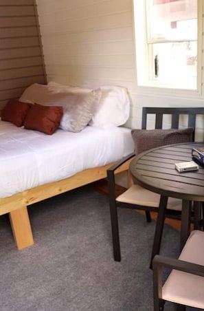 Cozy retreat with a single bed, round table, and comfortable chair.