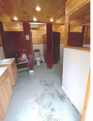 Cozy cabin with a kitchenette, toilet, shower, and mirror.
