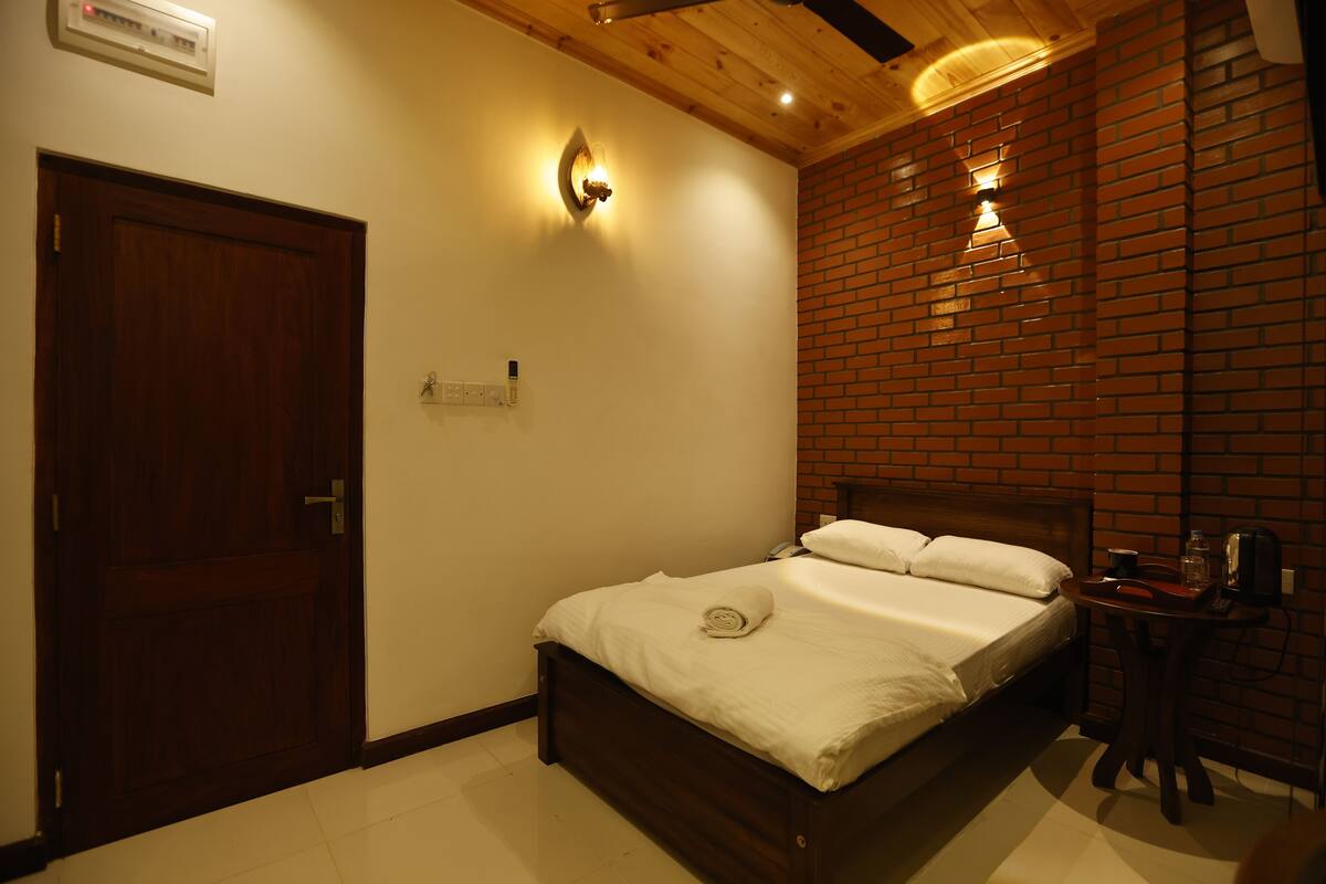 A bedroom with a wooden bed, a brick wall, and a door.