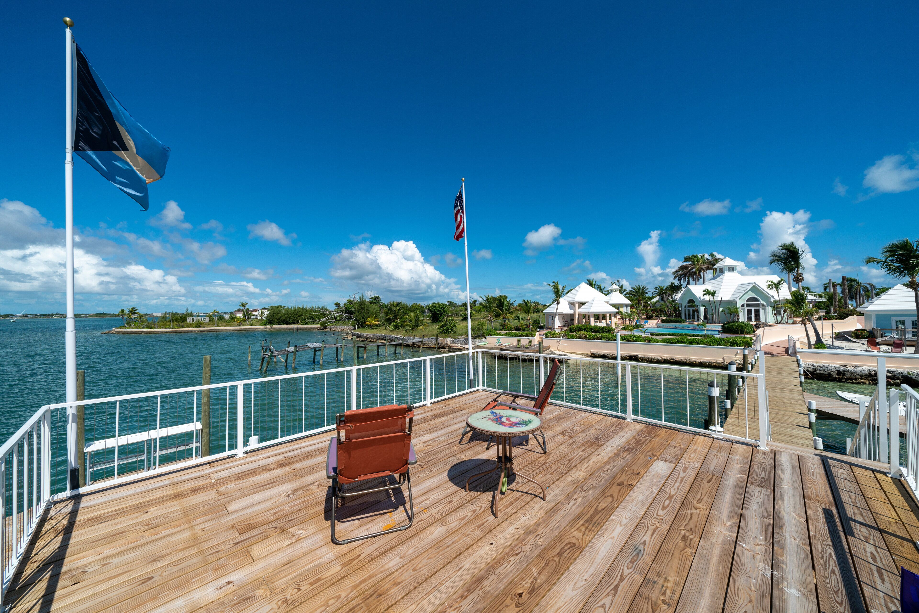 A wooden deck with a view of the water, a flag, and a flagpole.