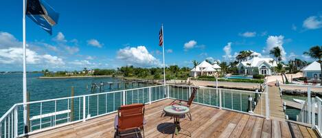 A wooden deck with a view of the water, a flag, and a flagpole.