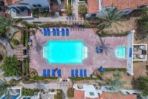 An aerial view of a resort with a central swimming pool, lounge chairs, and palm trees. - Desert Oasis B | Studio Legacy Villa (La Quinta)