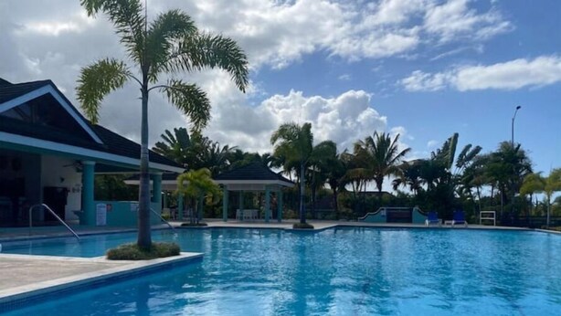 A swimming pool with clear water, surrounded by palm trees and a gazebo. - Island Style Villa in Richmond Estate Palms (St. Ann Parish)