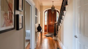 A hallway with wooden flooring, white walls, and a wooden door at the end. - Church St Collection - 109 Full House (Fairhope)
