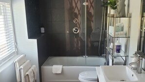 Une salle de bain moderne équipée d’une baignoire, de toilettes et d’un lavabo.