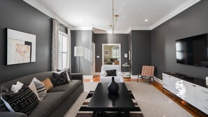 Ein modernes Wohnzimmer mit einem grauen Sofa, einem schwarzen Couchtisch und einem Fernseher.