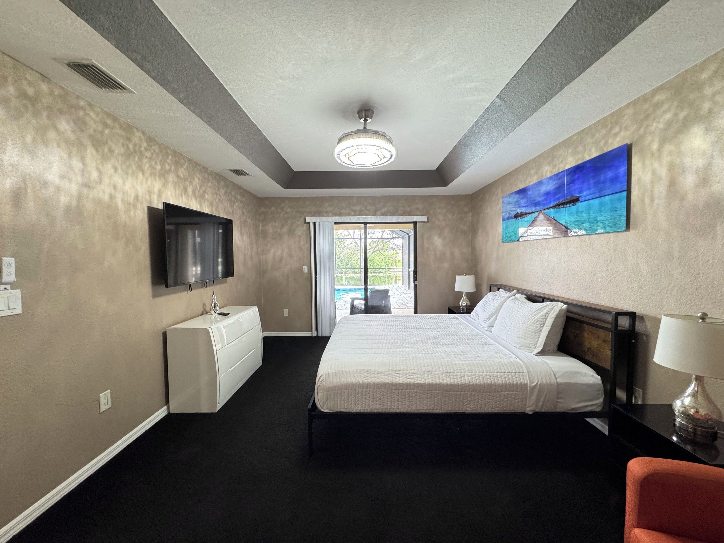 Quarto de hotel com uma cama, televisão, um quadro e vista para o exterior.