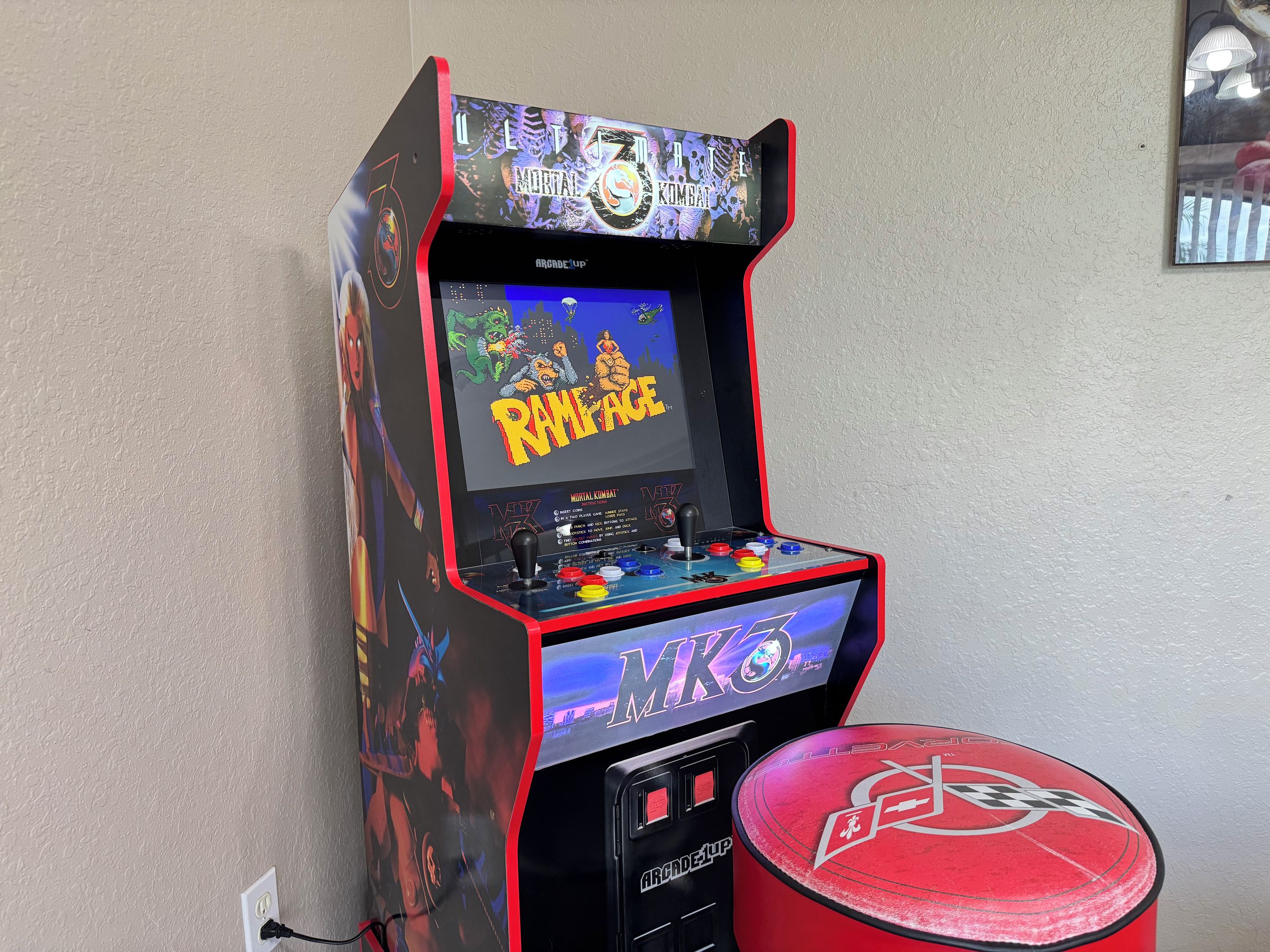 Una máquina de videojuegos retro con el juego Mortal Kombat, un joystick y un tambor rojo.