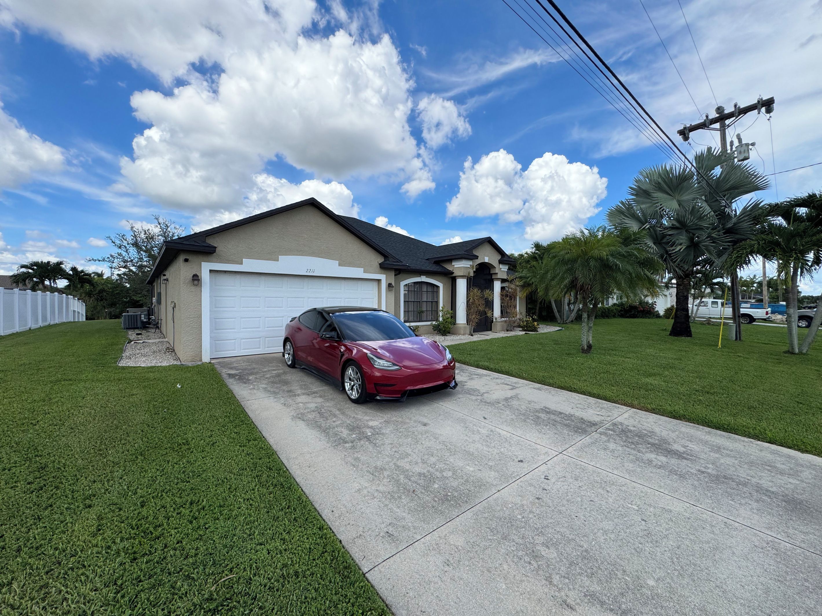 A residential house with a garage, a driveway, and a red car parked in front.