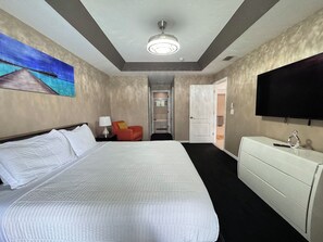 Habitación de hotel con una cama grande, televisión, escritorio y un cuadro en la pared.
