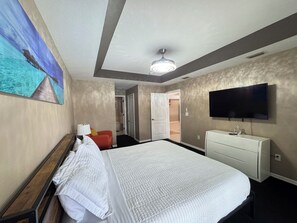 A hotel room with a bed, a television, a desk, and a painting on the wall.