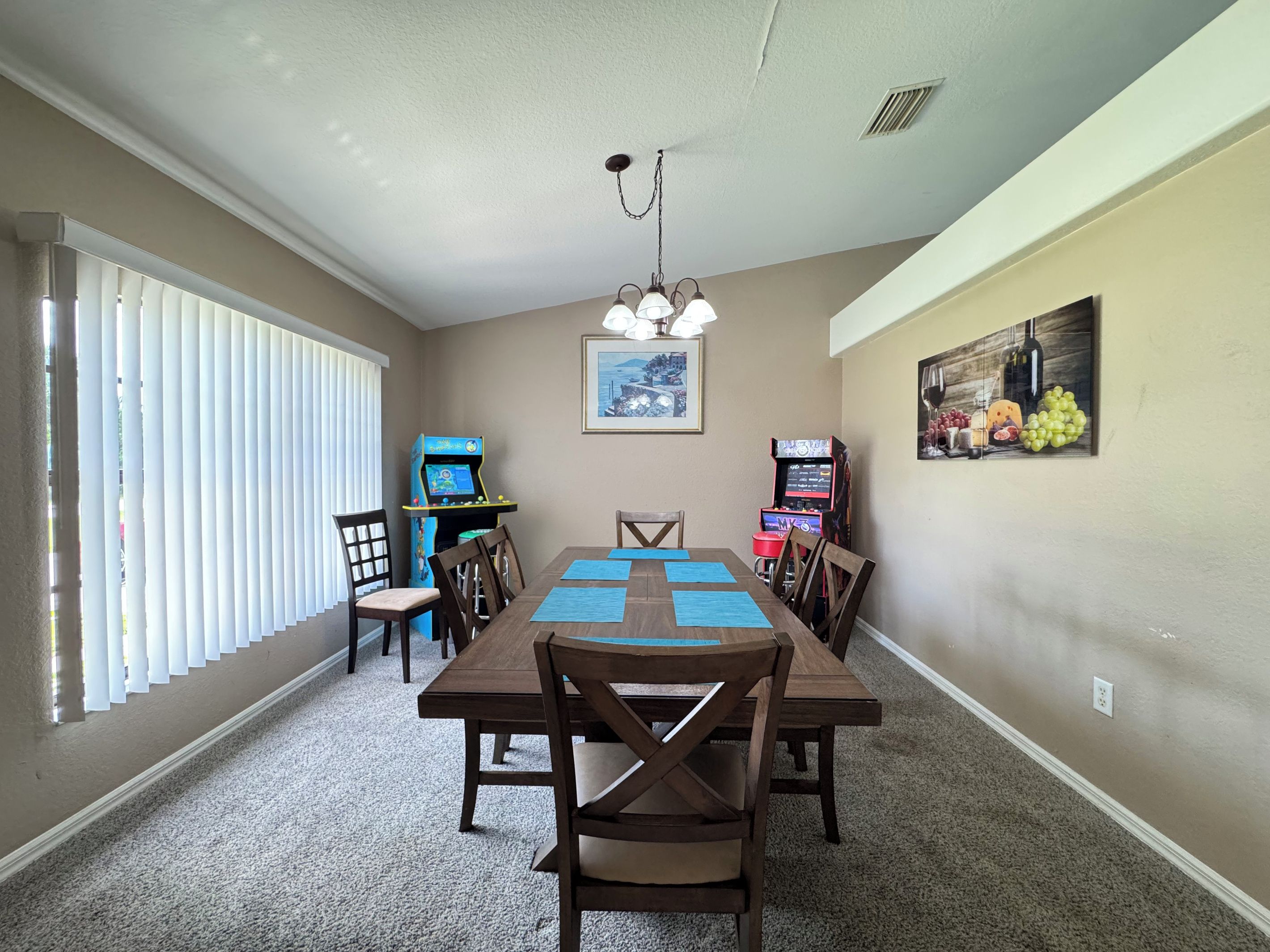 A dining area with a table, chairs, and two arcade machines.