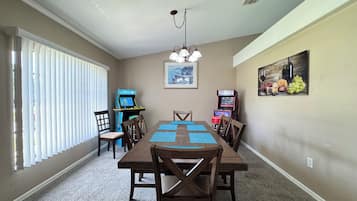 A dining area with a table, chairs, and two arcade machines.