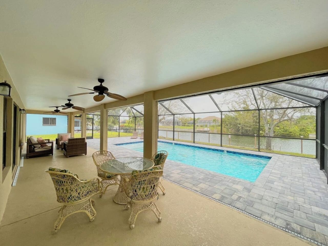 A covered patio area with a pool, wicker furniture, and a view of the outdoors.