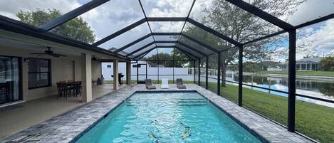 A covered swimming pool with a view of a lake and a white fence in the background.