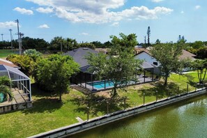 A residential area with a swimming pool, houses, and a canal.