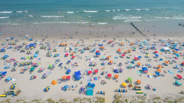 En strand med mange farverige parasoller og strandstole, der viser et populært turistmål.