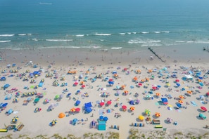 Una spiaggia con numerosi ombrelloni e lettini colorati, indice di una meta turistica molto frequentata.
