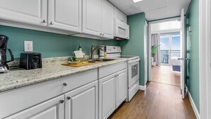 A modern kitchen with white cabinets, a granite countertop, a coffee maker, a toaster, and a stove.