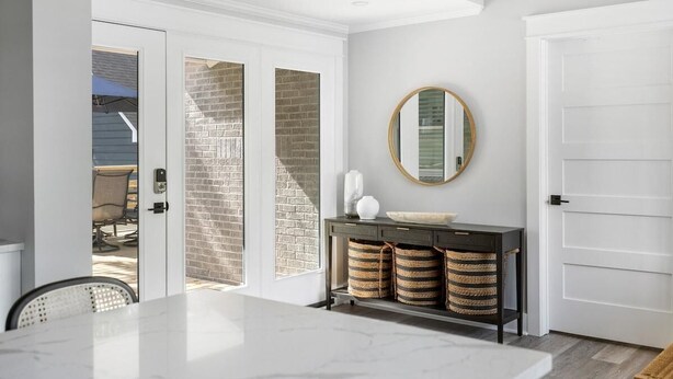 A modern kitchen with a marble countertop, a black console table with baskets, and a round mirror on the wall. - Palmetto Grove,  Walk to Shem Creek, Mins to Dwt (Mount Pleasant)