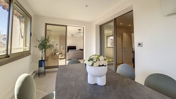 A modern dining area with a marble table, grey chairs, and a white vase with flowers. - N&J - BELLE ETOILE- Central - Premium (Niza)