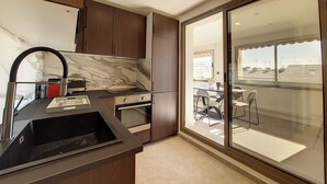 A modern kitchen with a marble backsplash, wooden cabinets, and a built-in oven. - N&J - BELLE ETOILE- Central - Premium (Niza)