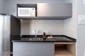 Una cocina moderna con microondas integrado, electrodomésticos de acero inoxidable y encimera negra.