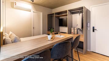 Quarto moderno com escrivaninha de madeira, cadeiras, guarda-roupa e cabideiro.