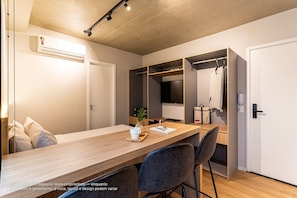 A modern room with a wooden desk, chairs, a wardrobe, and a hanging coat rack.