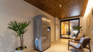 A reception area with a modern design, including a reception desk, a potted plant, and seating area. - Next Paulista by Viva - Apartamentos completos ao lado da Av Paulista e MASP (São Paulo)