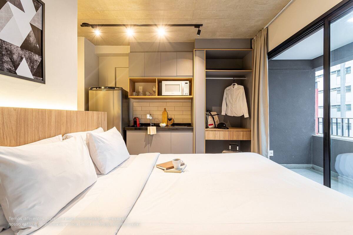Une chambre d’hôtel comprenant un lit, une table de chevet, un four à micro-ondes, un petit coin cuisine, un placard et une vue sur l’extérieur.