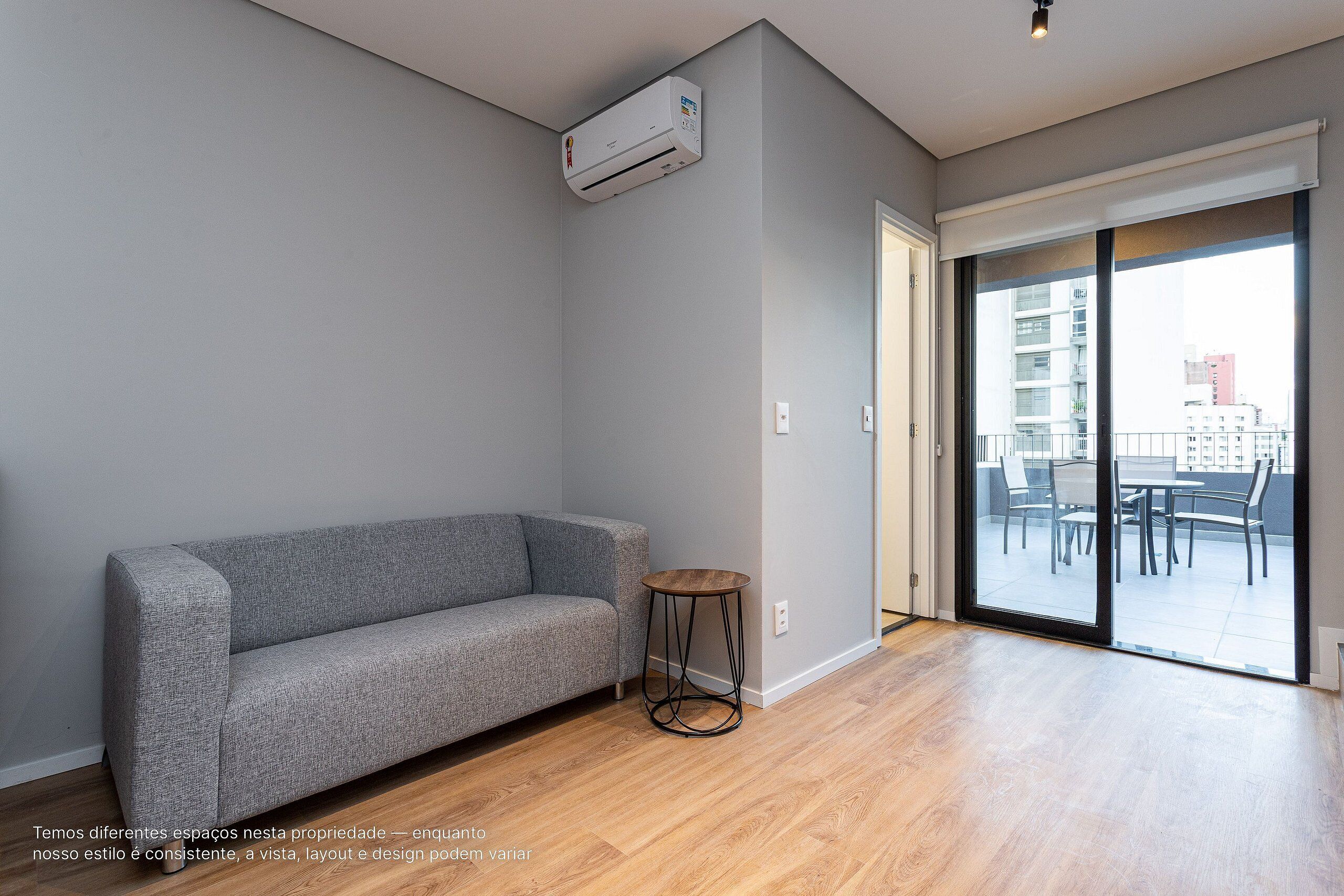 A grey sofa, a small round table, and a sliding glass door to an outdoor area.