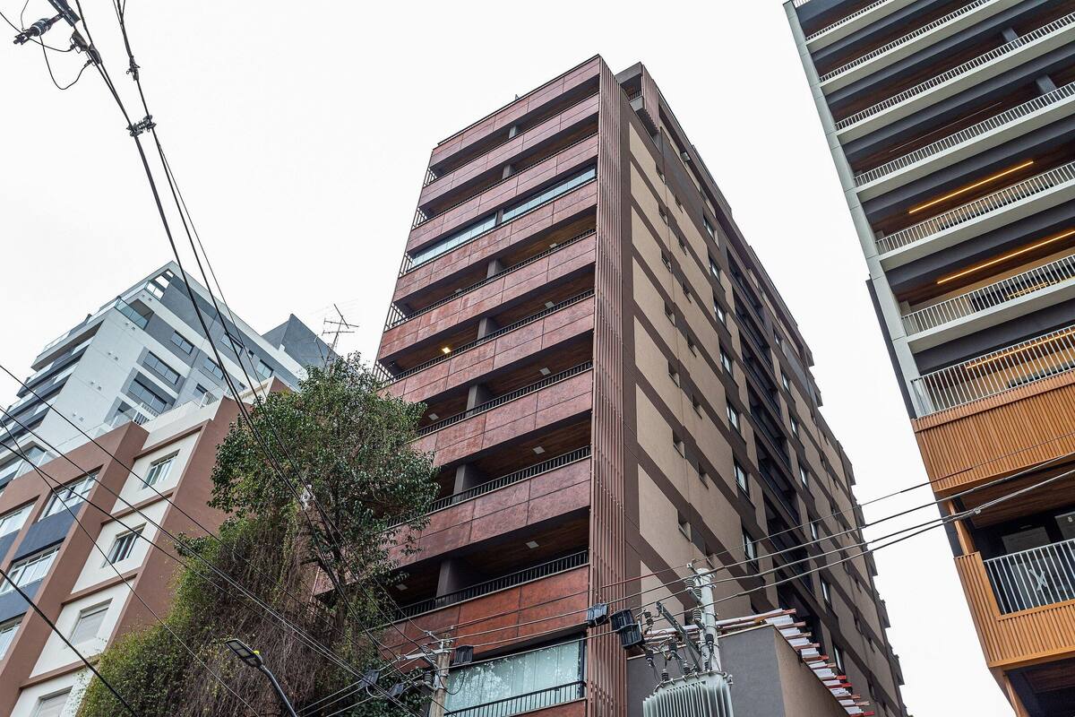 Ein mehrstöckiges Gebäude mit moderner Architektur, das Balkone und eine Mischung verschiedener Fensterformen aufweist.