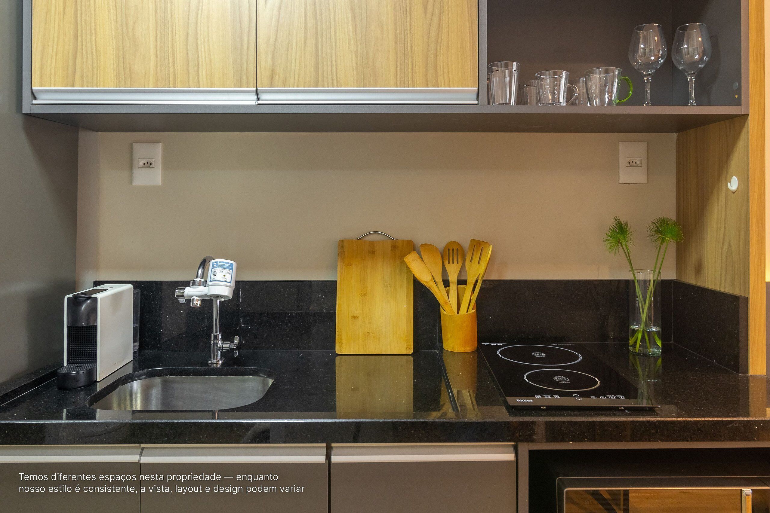 A kitchen with a black countertop, wooden cabinets, a built-in stove, and a sink.