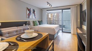 A modern hotel room with a sofa, dining table, and a bed. - Next Paulista by Viva - Apartamentos completos ao lado da Av Paulista e MASP (São Paulo)