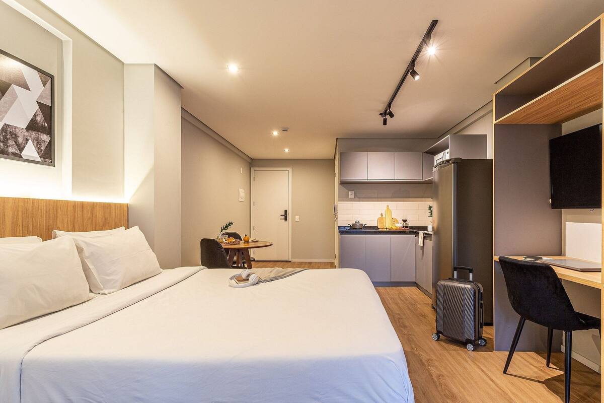 Une chambre d’hôtel équipée d’un lit, d’un bureau, d’une kitchenette et d’un téléviseur.