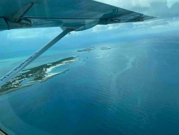 Vista aérea de una zona costera con aguas azul turquesa y una isla con edificios dispersos.
