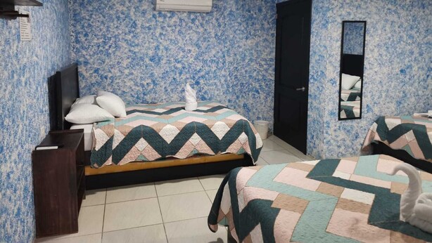 Hotellihuone, jossa on kaksi sänkyä, televisio, vaatekaappi ja ilmastointilaite.
