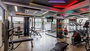 A modern gym with various exercise equipment, large windows, and a view of the cityscape. - Ator - Chic Studio in Vila Olimpia (São Paulo)