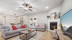 Una sala de estar con chimenea, dos sofás, una mesa de centro y un televisor.
