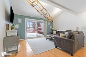 A living room with a sofa, a television, a fireplace, and a large window.