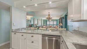 Una cocina amplia con una isla central, armarios blancos y un lavavajillas de acero inoxidable.