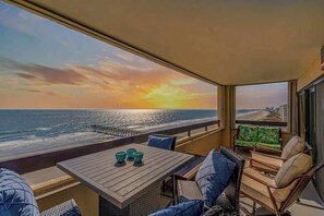 A balcony with a view of the ocean and sunset, furnished with a table and chairs. - Sea Pointe Unit 808 - Oceanfront (North Myrtle Beach)