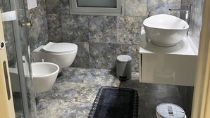 Une salle de bain avec une douche, deux toilettes, un lavabo et un miroir.