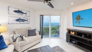 A living room with a sofa, a coffee table, a TV, and artwork on the wall. - Captains Quarters Ocean Pointe 4405 (Tavernier)
