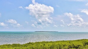 Paisaje costero con cielo despejado, mar en calma y una isla distante.