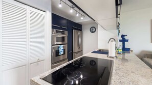 A modern kitchen with stainless steel appliances, a built-in oven, and a black induction cooktop.