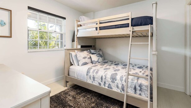 Habitación con literas, una ventana, un escritorio y una colcha estampada.