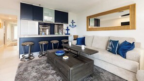 A modern living room with a sofa, coffee table, and bar stools. - Captains Quarters Ocean Pointe 4405 (Tavernier)